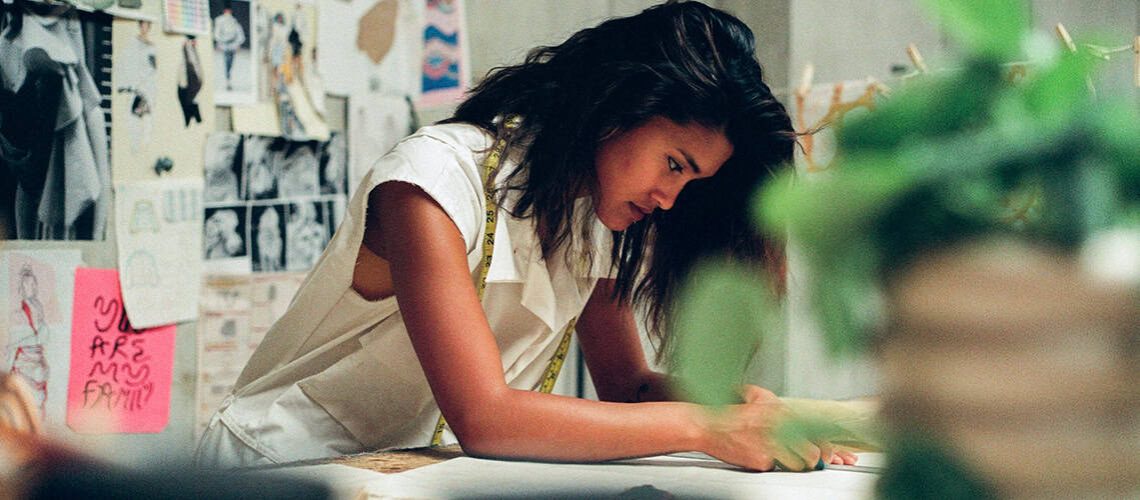 Woman writing at desk in a creative workspace, focused on her work.