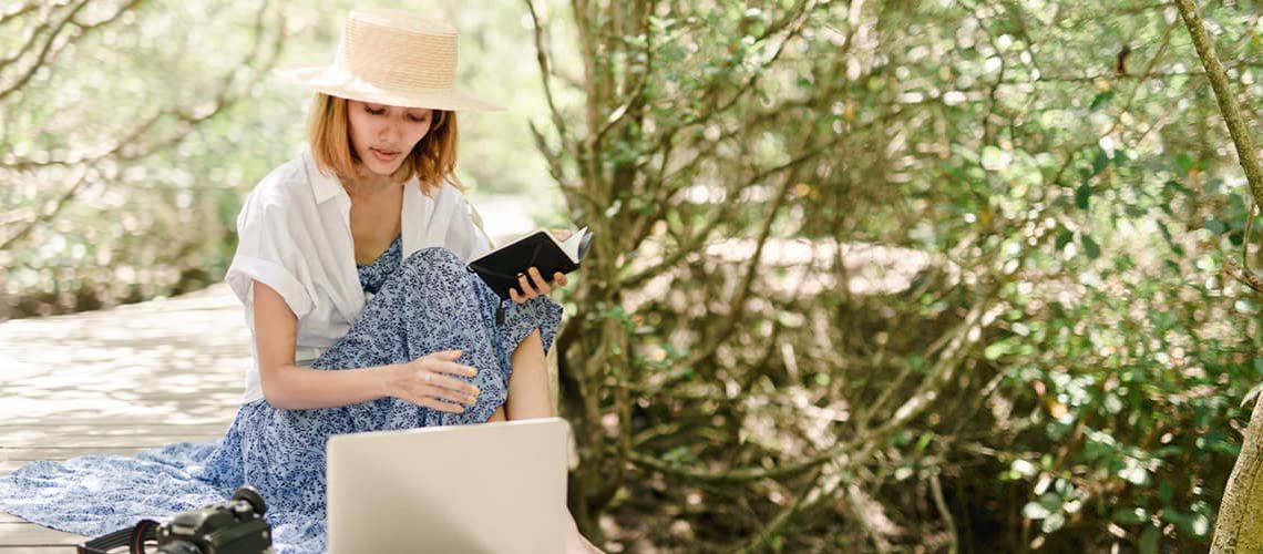 Woman using tablet outdoors for book writing with a ghostwriter.