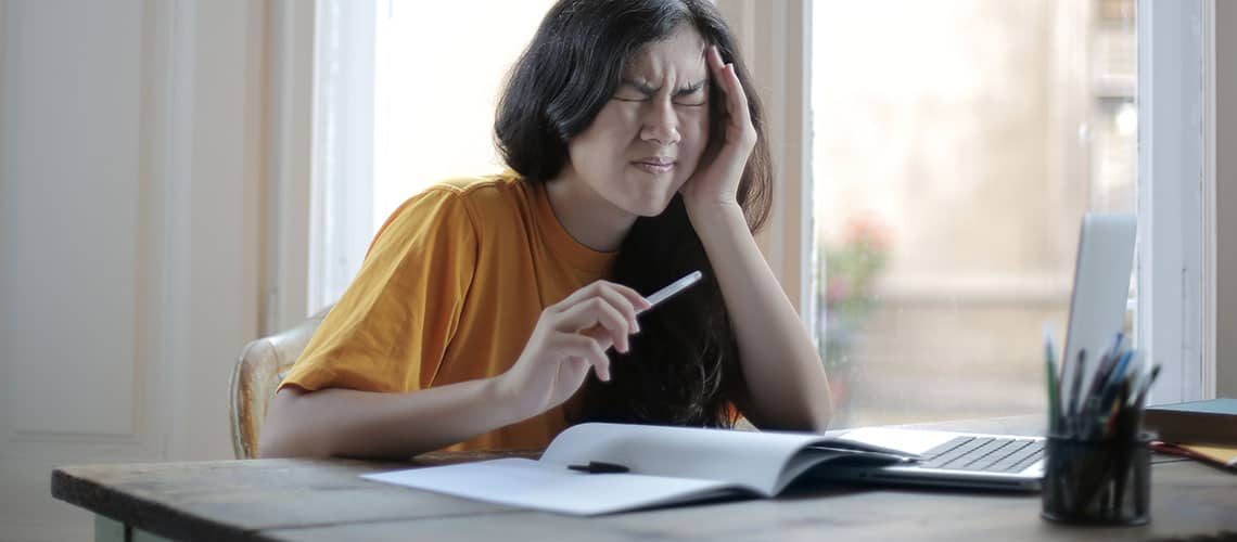 Frustrated woman struggling with writing pressure at her desk.